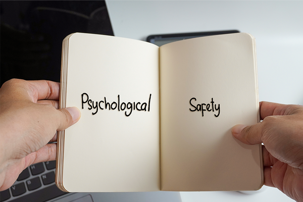 Hände, die ein Buch mit dem Wort Psychologische Sicherheit halten.