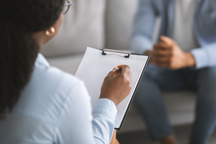 Therapeutin, die sich mit männlichem Patienten unterhält.